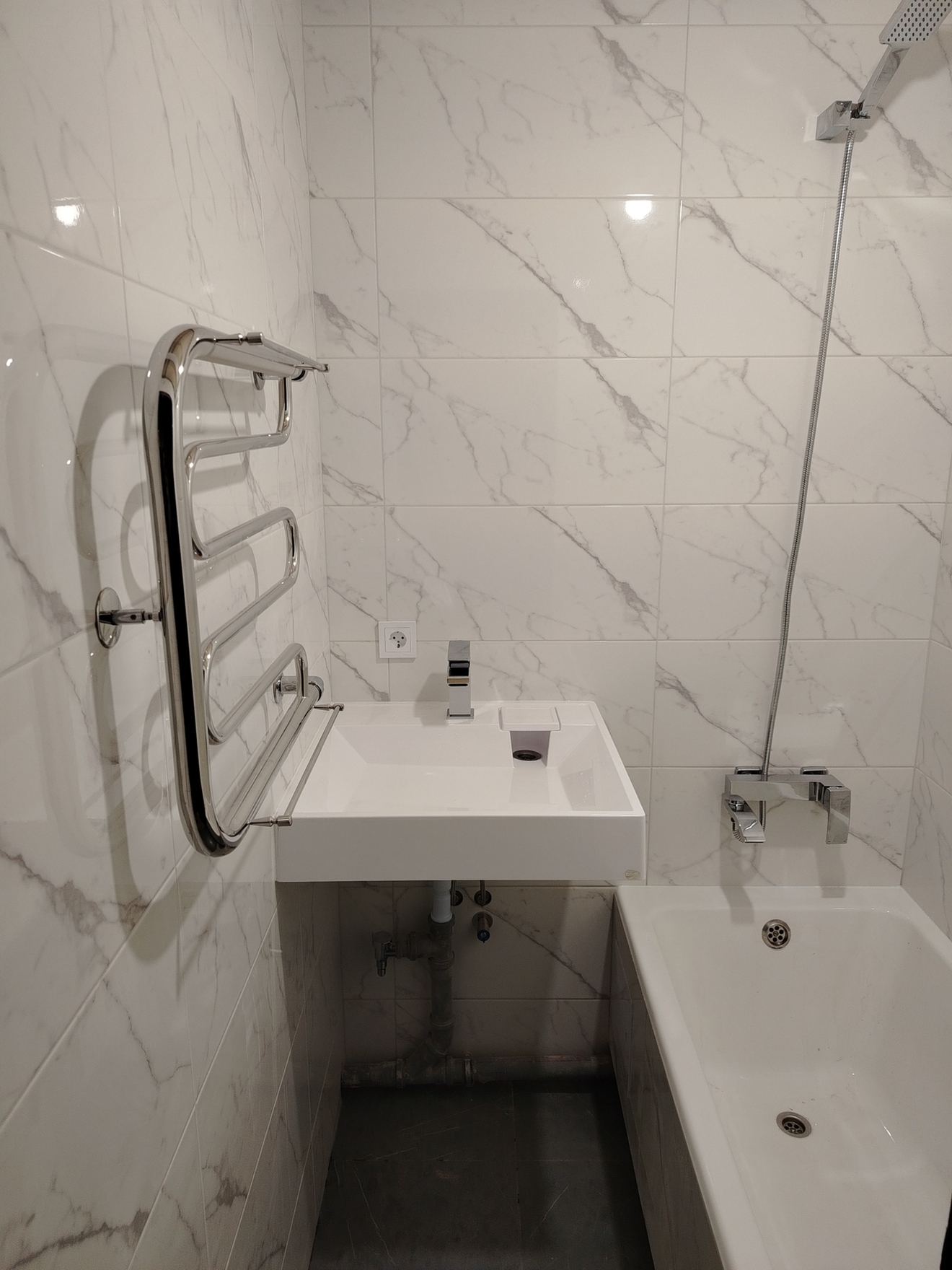 Укладка плитки на стены, разводка сантехники, монтаж умывальника над стиральной машиной, перенос полотенцесушителя.