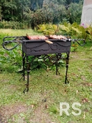 Простой загородный мангал: кованый металл, прочная конструкция для лавочки у дома.
Использовались толстая сталь, сварочный аппарат, антикоррозийная обработка для долговечности.