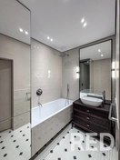 Стильная ванная комната: сочетание светлых оттенков, глянцевой плитки и современной сантехники, подчеркнутое точечным освещением для создания атмосферы роскоши и комфорта.