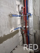 На фото монтаж разводки труб для сантехники в жилом комплексе "Парк Челюскинцев", с использованием полипропиленовых труб и фитингов.
Трубы закреплены на стене с помощью клипс, обеспечена герметичность соединений для горячей и холодной воды.