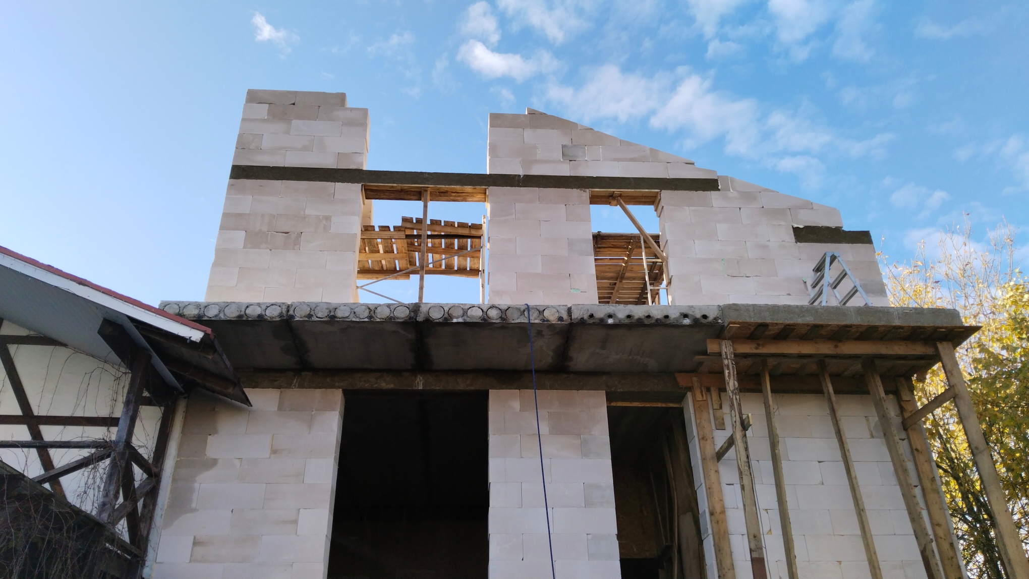 На фото показан процесс укладки блоков и зиливки армопояса на стены здания с использованием деревянной опалубки для укрепления конструкции.