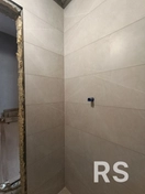 На фото — результат укладки керамической плитки в ванной. Стены выровняли штукатуркой, нанесли гидроизоляцию, после чего уложили плитку на клей. Использовались качественные материалы для долговечности и защиты от влаги.