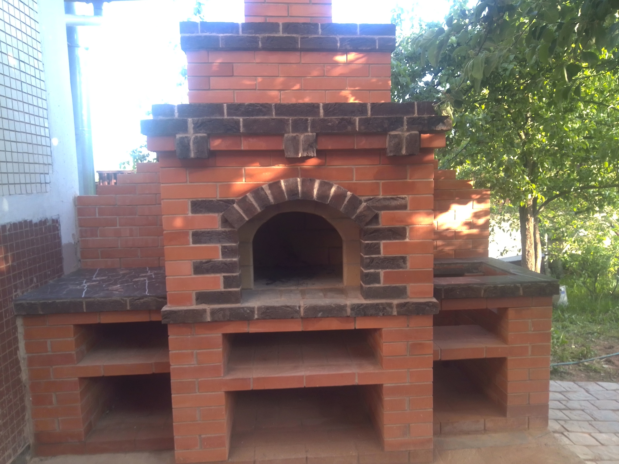 Уличная печь из огнеупорного и облицовочного кирпича, кладка с арочным сводом на глиняно-песчаном растворе, укреплена металлическими уголками для долговечности.