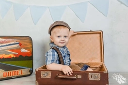 Малыш в сказочном путешествии, сидящий в своем чемодане приключений.