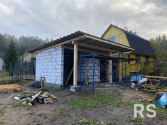 На фото запечатлен процесс строительства навеса. Возведены стены из газоблока, на которые уже установлена деревянная стропильная система. Закончил монтаж обрешетки под кровельное покрытие.