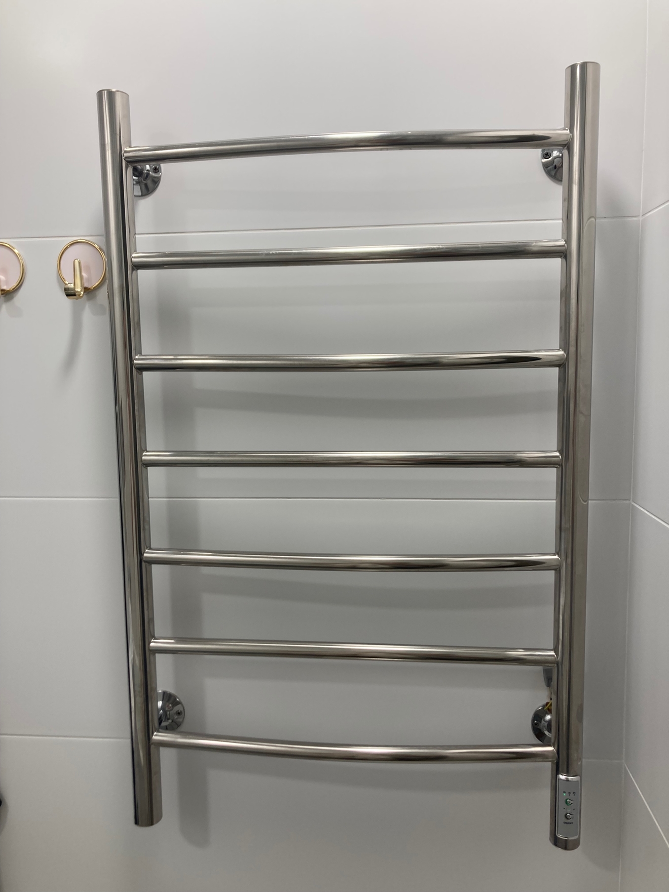 На фото показан процесс установки нержавеющего полотенцесушителя лесенкого типа в ванной комнате.