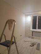 На фотографии изображена работа по поклейке флизелиновых обоев. Для этого использовались специальный клей, рулонные обои, инструменты для резки и нанесения клея.