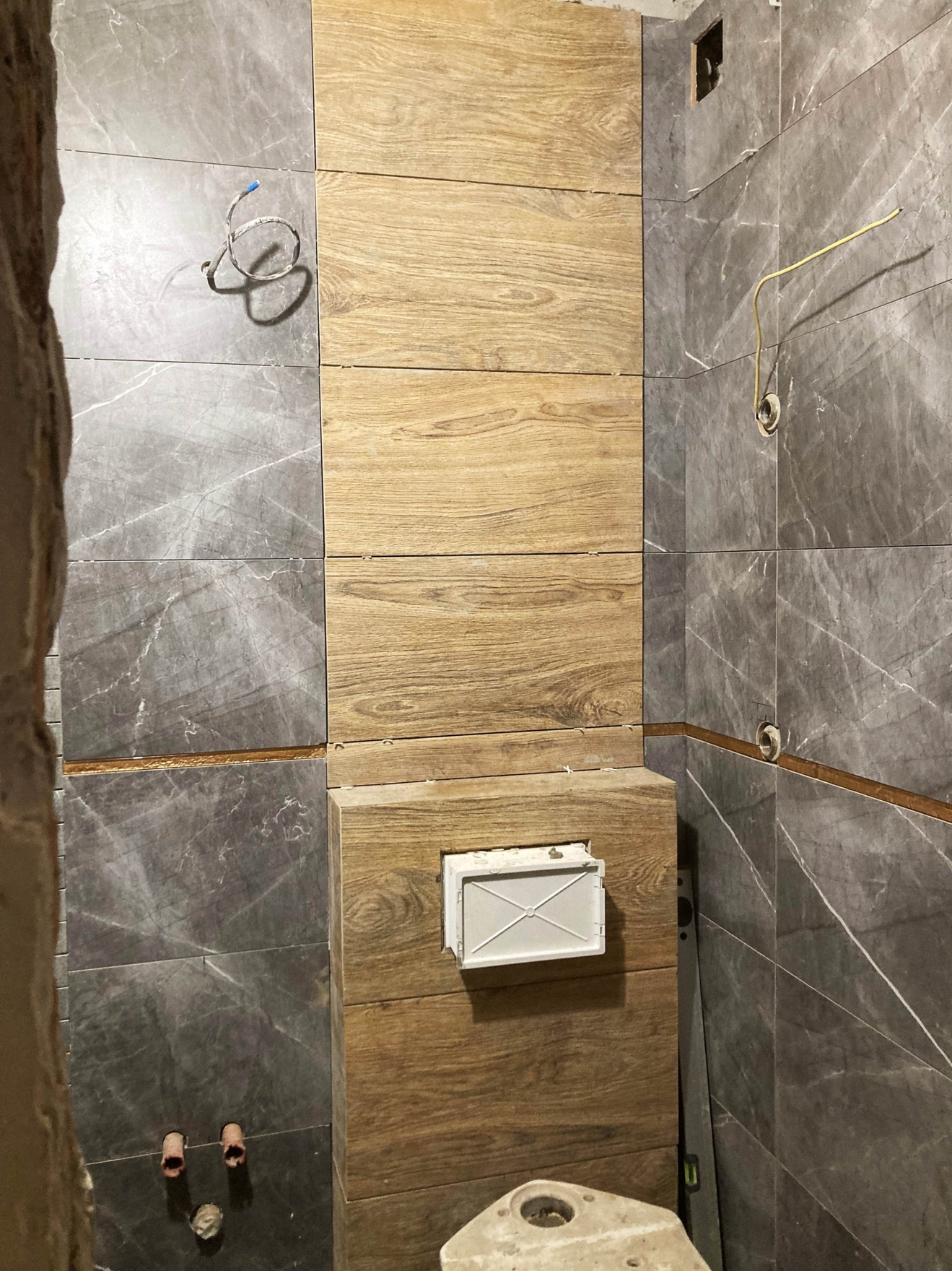 Укладка плитки на пол и стены в ванной, а также инсталляция унитаза. Установка потайного смотрового люка над инсталляцией.