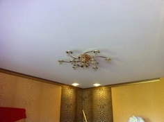Белый тканевый натяжной потолок в спальне. Освещение люстра и светильники
