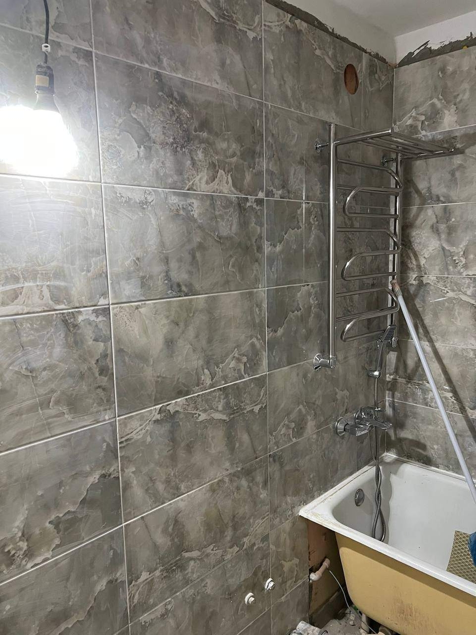 Проведена укладка керамической плитки размером 900 × 300 мм на стены ванной комнаты; работы выполнены с соблюдением горизонтальной и вертикальной геометрии.